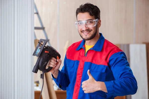 Jovem reparador trabalhando com uma serra elétrica — Fotografia de Stock