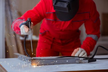 Kaynak tabancası elektrot ve kask takan genç bir tamirci.