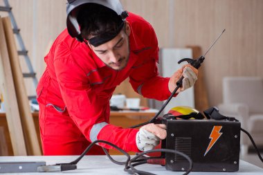Kaynak tabancası elektrot ve kask takan genç bir tamirci.