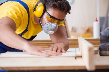 Genç bir marangoz dairesel testere ile çalışıyor.