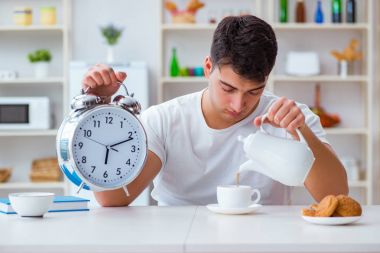 Çalar saati olan bir adam kahvaltıda uyuyakalıyor.