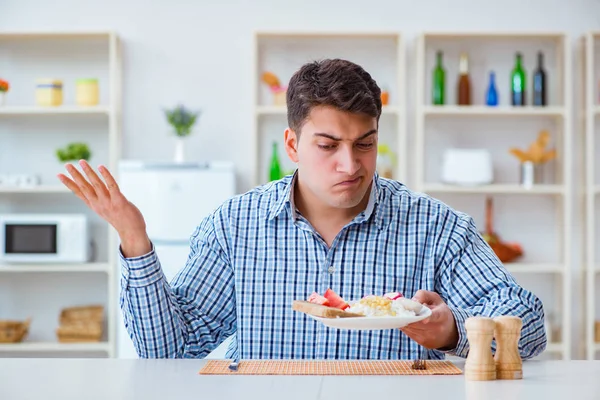 Jovem marido comendo comida insípida em casa para o almoço — Fotografia de Stock