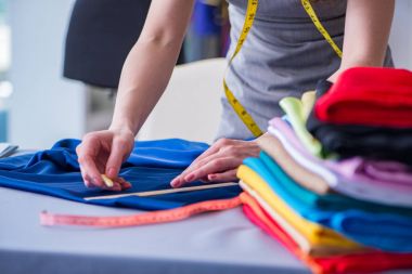 Kadın terzi dikiş dikmek için dikiş dikiyor.