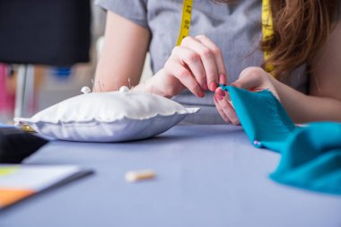 Kadın terzi dikiş dikmek için dikiş dikiyor.