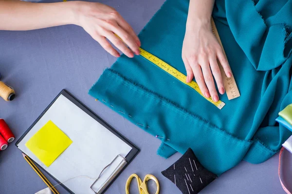 Kadın terzi dikiş dikmek için dikiş dikiyor.