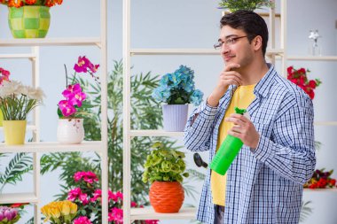Çiçekçide çalışan genç bir adam.