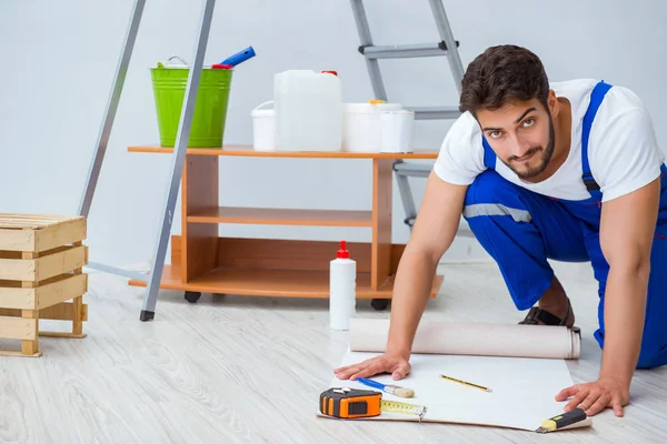 Tamirci, duvar kağıdıyla evde tadilat yapıyor.