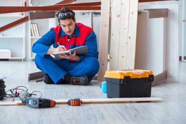 İnşaatta defter planlama yapan genç bir marangoz.