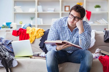 Genç adam dağınık bir odada çalışıyor.