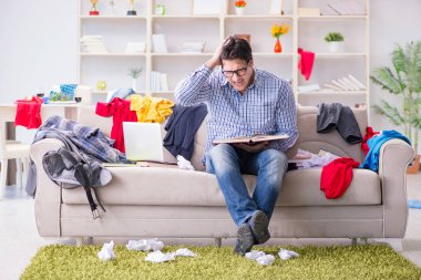 Genç adam dağınık bir odada çalışıyor.