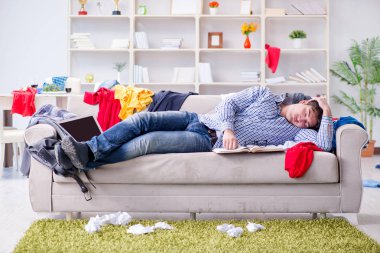 Genç adam dağınık bir odada çalışıyor.