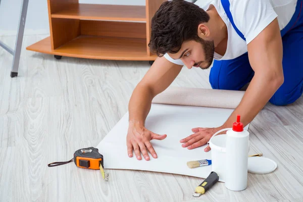 Tamirci, duvar kağıdıyla evde tadilat yapıyor.