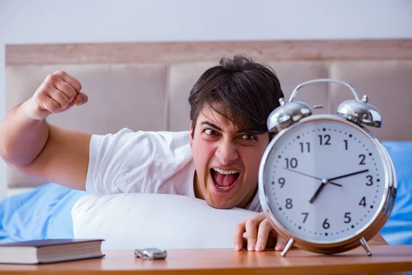 Homme au lit frustré souffrant d'insomnie avec un cloc d'alarme — Photo