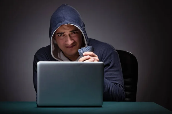 Young man wearing a hoodie sitting in front of a laptop computer — Stock Photo, Image