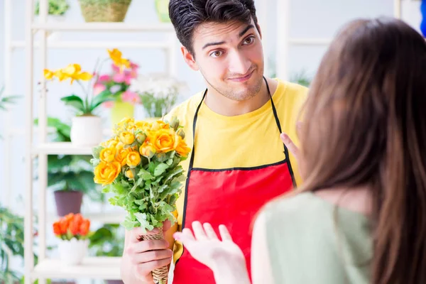 Çiçekçi dükkanında çiçek satıyor.