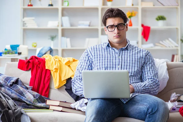 Genç adam dağınık bir odada çalışıyor.