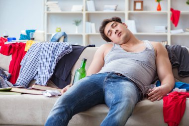 Dağınık bir odada alkol alan genç bir öğrenci.