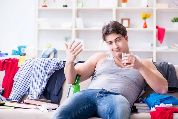Dağınık bir odada alkol alan genç bir öğrenci.