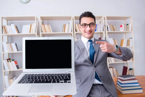 Empresario con un portátil de pantalla en blanco que trabaja en la biblioteca — Foto de Stock