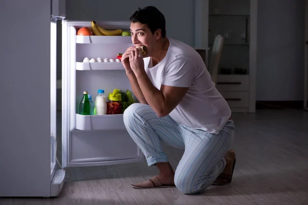 Homem na geladeira comendo à noite — Fotografia de Stock