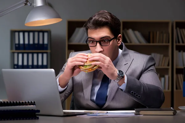 Uomo d'affari a tarda notte mangiare un hamburger — Foto Stock