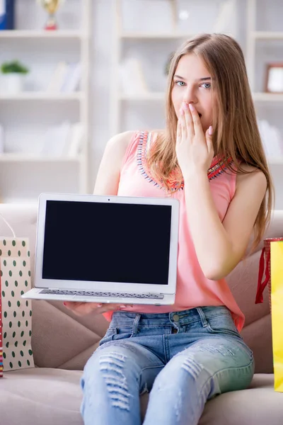 Alışveriş poşetleriyle evde, kanepenin üzerinde genç bir kadın.