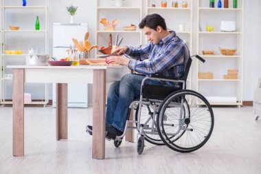 Genç engelli koca yemek salatası hazırlıyor.