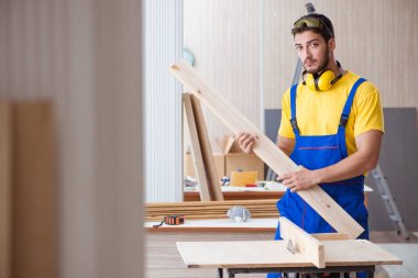 Genç tamirci marangoz odun kesiyor.