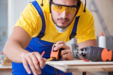 Genç bir marangoz dairesel testereyle odun kesiyor.