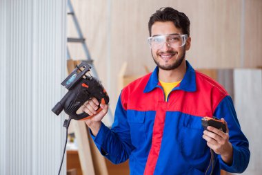 Elektrikli testereyle çalışan genç bir tamirci.