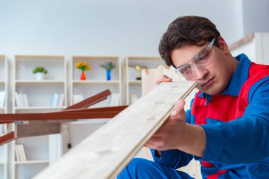 Genç marangoz ahşap kalaslarla çalışıyor.