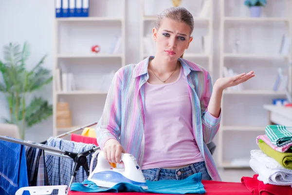 Üzücü kadın evde kıyafetleri ütülüyor.