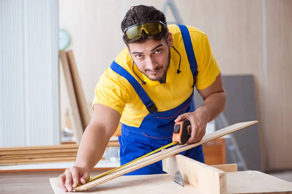 Carpintero joven reparador que trabaja cortando madera en sierra circular — Foto de Stock