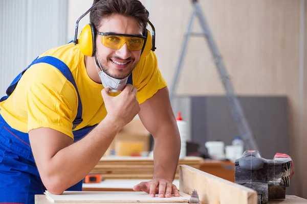 Genç bir marangoz dairesel testere ile çalışıyor.