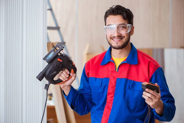 Elektrikli testereyle çalışan genç bir tamirci.