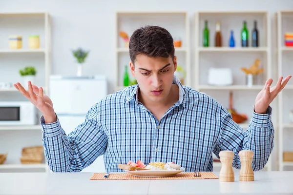 Fiatal férj eszik íztelen étel otthon ebédre — Stock Fotó