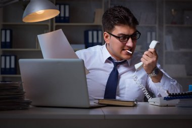İş adamı telefonda konuşuyor ve ofiste sigara içiyor.