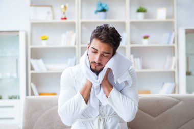 Duştan sonra bornozlu genç adam saçlarını havluyla kurutuyor.