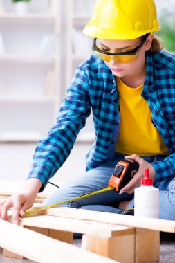 Tamirci kadın marangoz ahşap döşemeleri kesiyor.