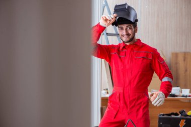 Kaynak tabancası elektrot ve kask takan genç bir tamirci.