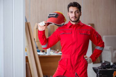 Kaynak tabancası elektrot ve kask takan genç bir tamirci.