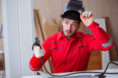 Kaynak tabancası elektrot ve kask takan genç bir tamirci.