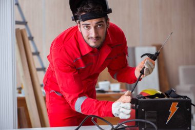 Kaynak tabancası elektrot ve kask takan genç bir tamirci.