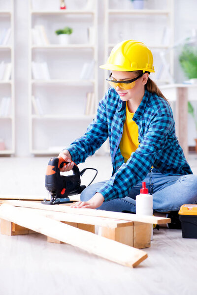 Female repairman carpenter cutting joining wooden planks doing r