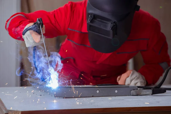 Kaynak tabancası elektrot ve kask takan genç bir tamirci.