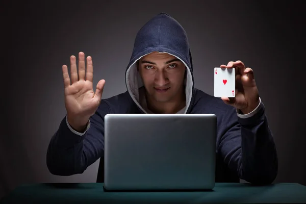 Jovem usando um capuz sentado na frente de um computador portátil — Fotografia de Stock