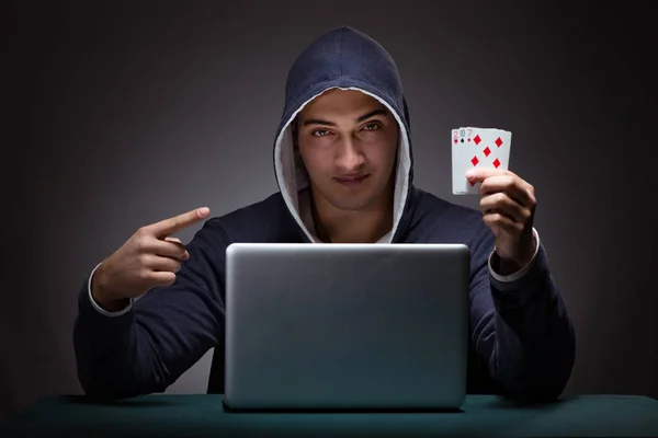 Jovem usando um capuz sentado na frente de um computador portátil — Fotografia de Stock