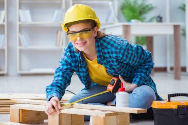 Tamirci kadın marangoz ahşap döşemeleri kesiyor.