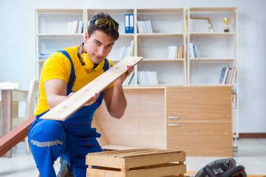 Tamirci marangoz ahşap tahtayı inceliyor.