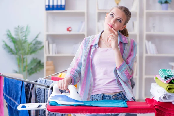 Üzücü kadın evde kıyafetleri ütülüyor.